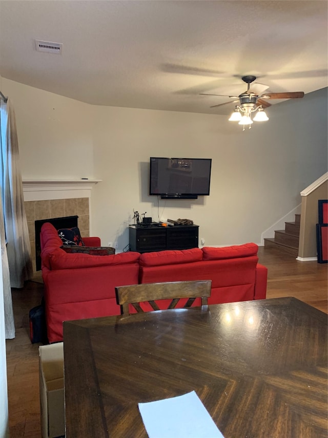 living room featuring a tile fireplace, ceiling fan, and dark hardwood / wood-style flooring