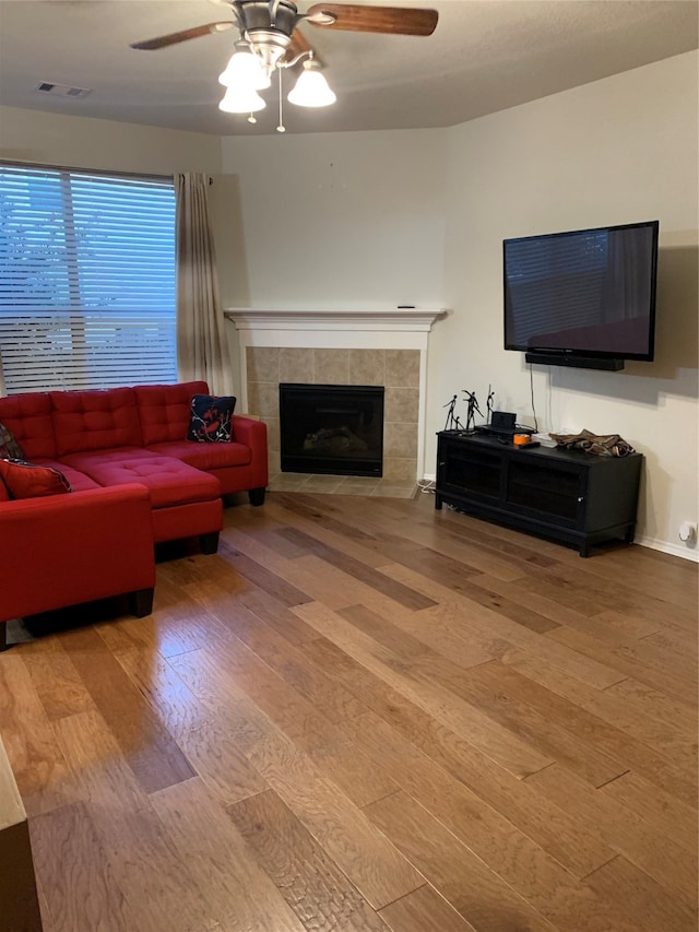 living room with a fireplace, ceiling fan, and light hardwood / wood-style floors