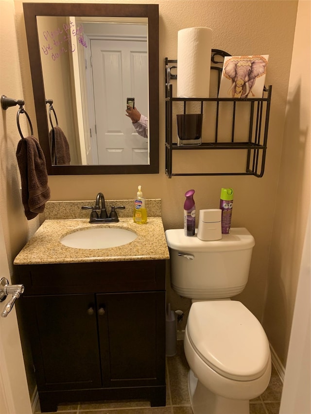 bathroom with toilet, vanity, and tile patterned floors