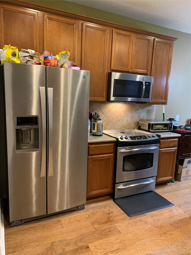 kitchen featuring appliances with stainless steel finishes, light hardwood / wood-style floors, and tasteful backsplash