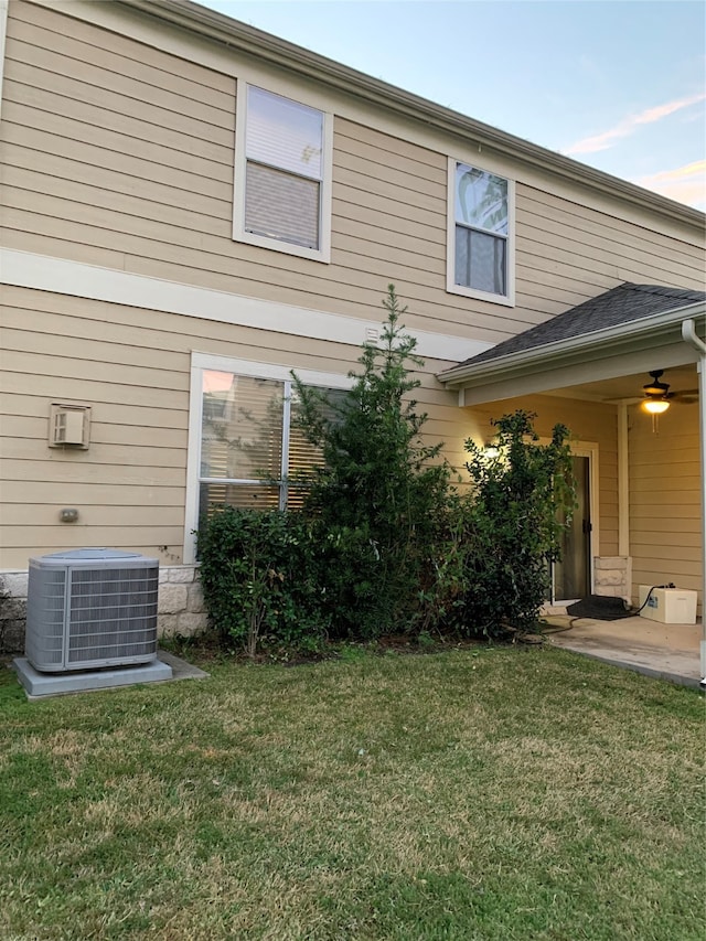 rear view of house with ceiling fan, a yard, and central AC