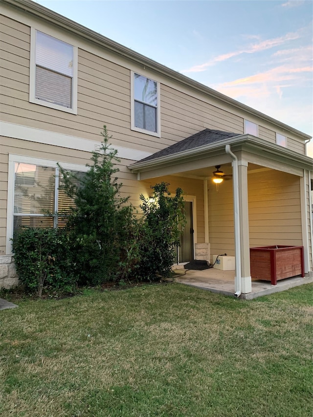 back of property with a jacuzzi, a patio, and a lawn