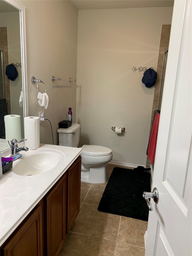 bathroom featuring toilet, a shower with door, vanity, and tile patterned flooring