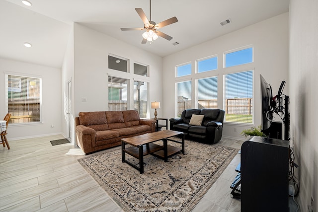 living room with a towering ceiling, plenty of natural light, and ceiling fan