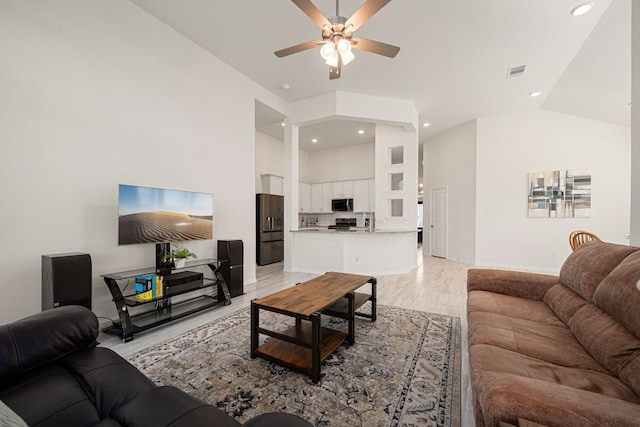 living room with ceiling fan, light wood-type flooring, and high vaulted ceiling