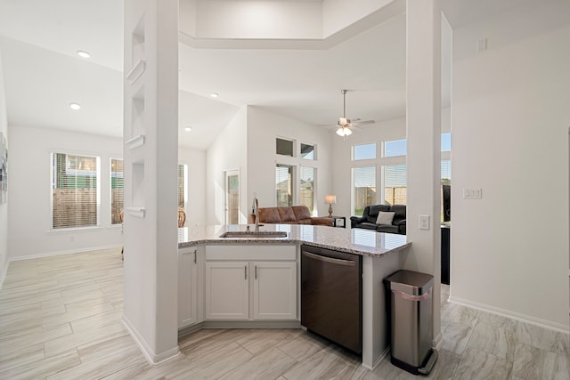 kitchen with white cabinets, sink, stainless steel dishwasher, high vaulted ceiling, and light stone countertops