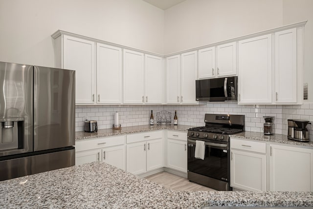 kitchen featuring light stone counters, stainless steel appliances, and white cabinets