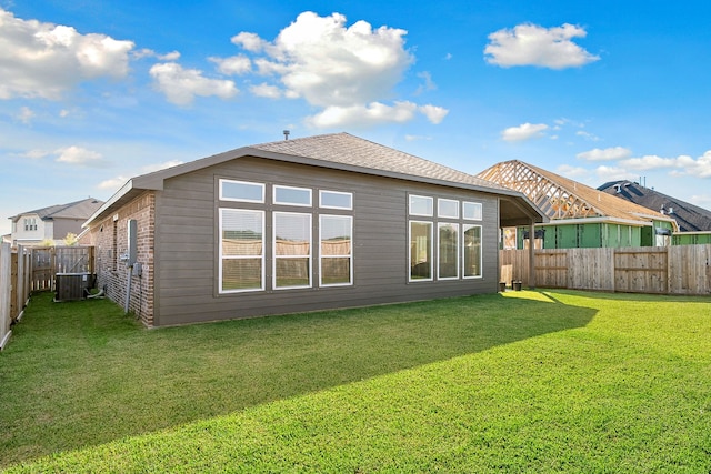 back of property featuring central AC unit and a lawn