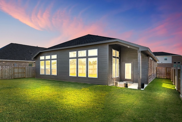 back house at dusk with a lawn