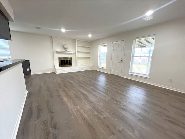 unfurnished living room with dark wood-type flooring, a fireplace, and built in features