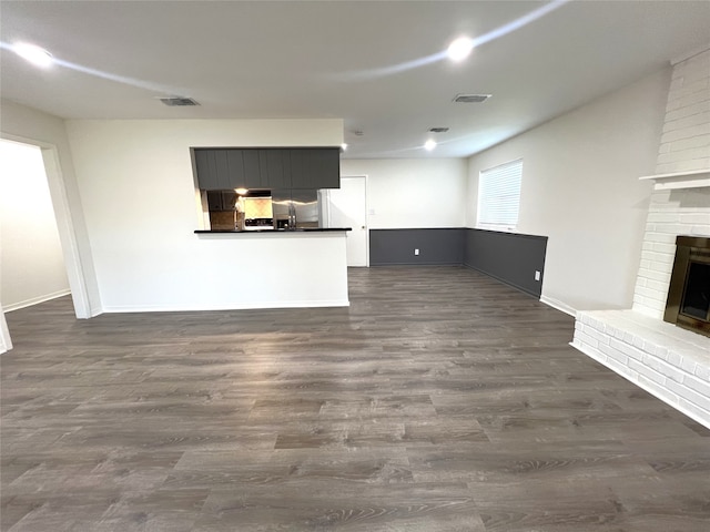 unfurnished living room with a brick fireplace and dark hardwood / wood-style floors