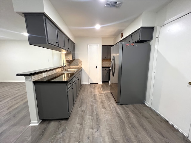 kitchen with gray cabinetry, backsplash, sink, stainless steel refrigerator, and dark hardwood / wood-style flooring