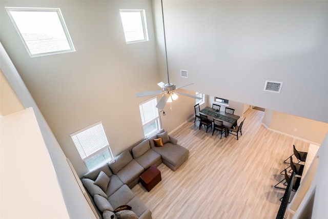 living room with hardwood / wood-style floors, ceiling fan, and a towering ceiling