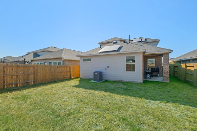 rear view of property with cooling unit, a yard, and a patio area