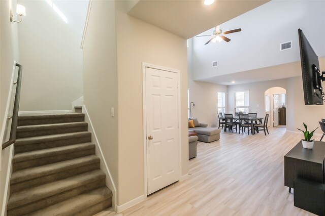 stairway with a high ceiling, ceiling fan, and hardwood / wood-style floors