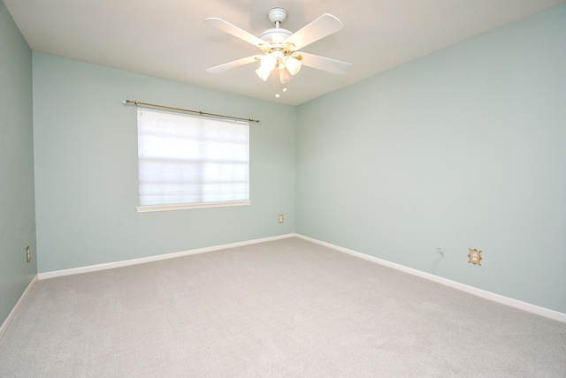 carpeted spare room featuring baseboards and a ceiling fan