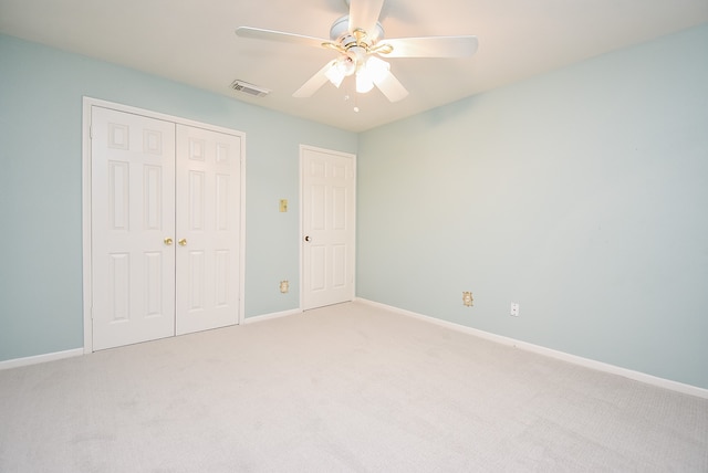 unfurnished bedroom with a closet, light colored carpet, visible vents, ceiling fan, and baseboards