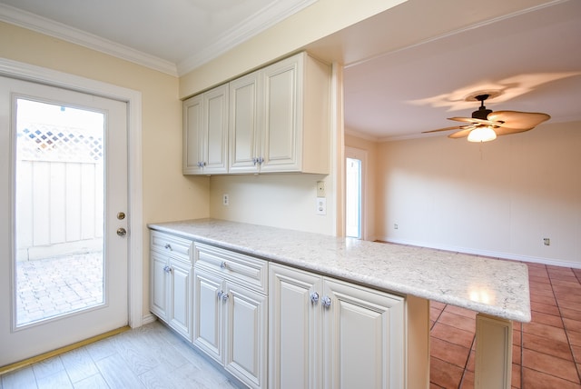 kitchen with a peninsula, ornamental molding, and white cabinets