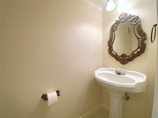 bathroom with ornamental molding, a sink, and baseboards