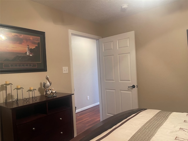 bedroom with a textured ceiling and dark wood-type flooring