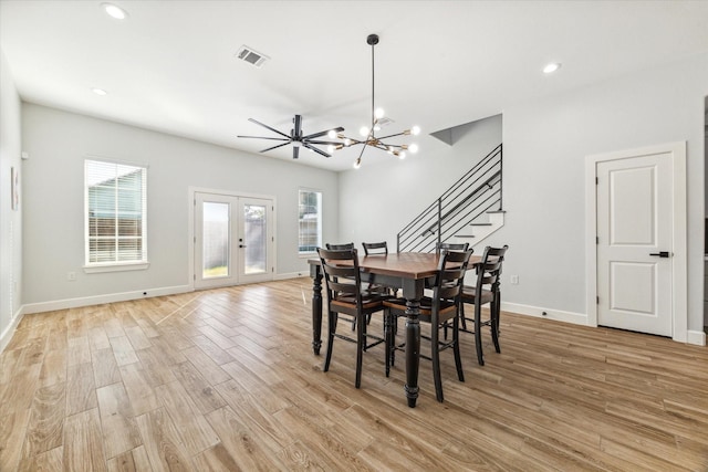 dining room featuring light hardwood / wood-style flooring, ceiling fan with notable chandelier, and french doors