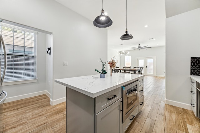 kitchen featuring pendant lighting, a kitchen island, gray cabinetry, and a healthy amount of sunlight