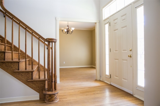 entrance foyer featuring a chandelier, light wood-type flooring, and ornamental molding