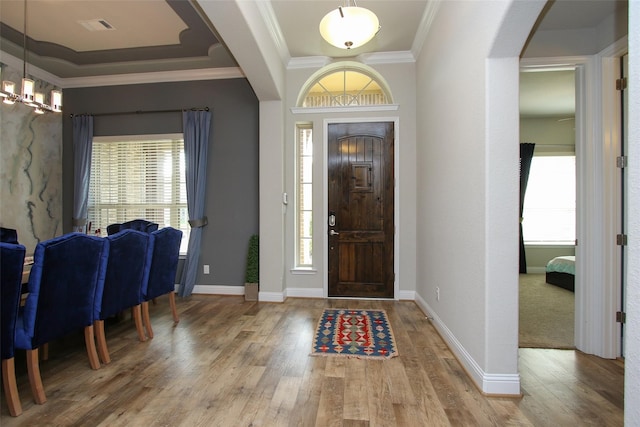 foyer entrance with a wealth of natural light, ornamental molding, and hardwood / wood-style flooring