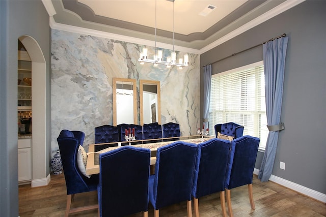 dining space with crown molding, a tray ceiling, and wood-type flooring