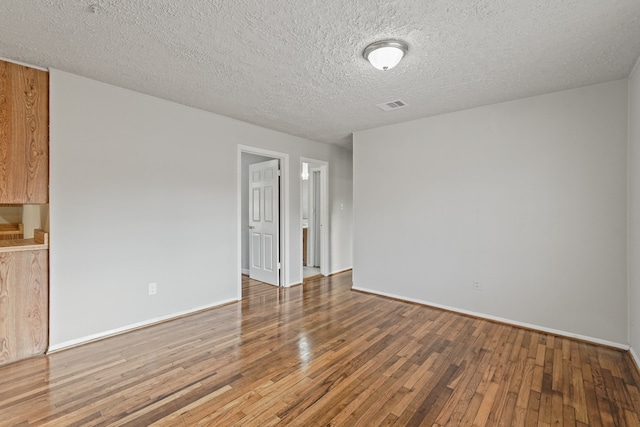 spare room with a textured ceiling and hardwood / wood-style flooring