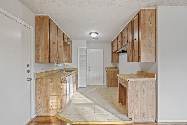 kitchen featuring a textured ceiling, sink, white dishwasher, and light hardwood / wood-style flooring