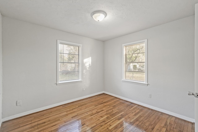 unfurnished room with a textured ceiling and light hardwood / wood-style flooring