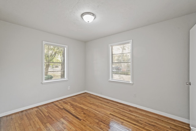 unfurnished room featuring wood-type flooring and a healthy amount of sunlight