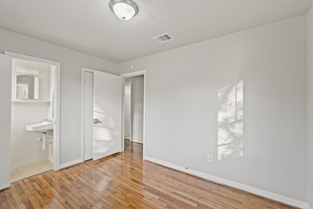 unfurnished bedroom with ensuite bath, sink, and light hardwood / wood-style floors