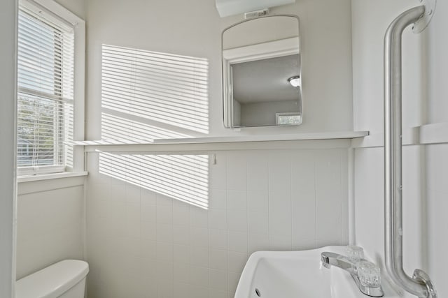 bathroom with tile walls and toilet