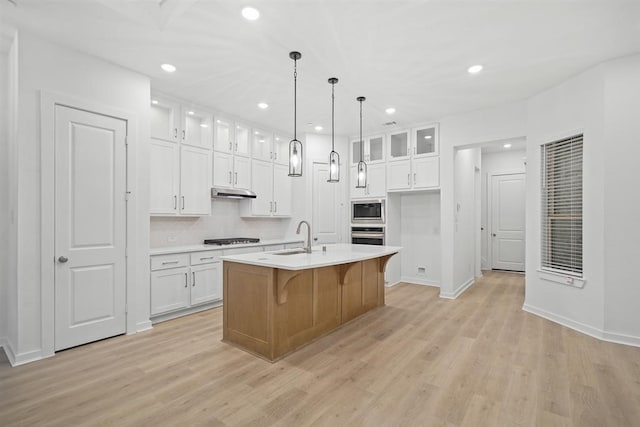 kitchen with sink, gas cooktop, an island with sink, white cabinets, and built in microwave