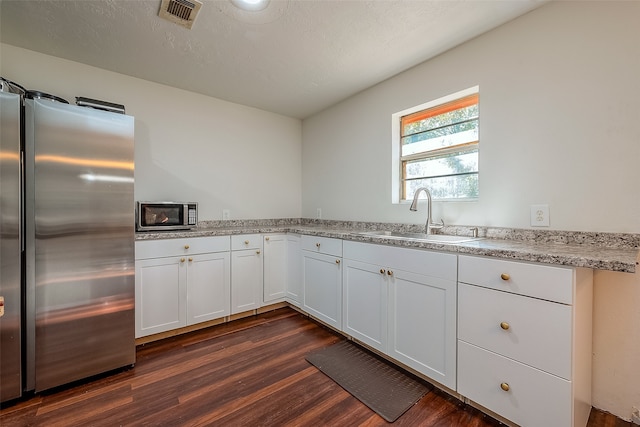 kitchen with sink, appliances with stainless steel finishes, dark hardwood / wood-style floors, and white cabinets