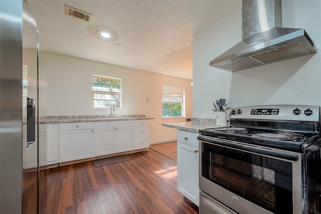 kitchen featuring wall chimney range hood, white cabinets, appliances with stainless steel finishes, light stone countertops, and dark hardwood / wood-style floors