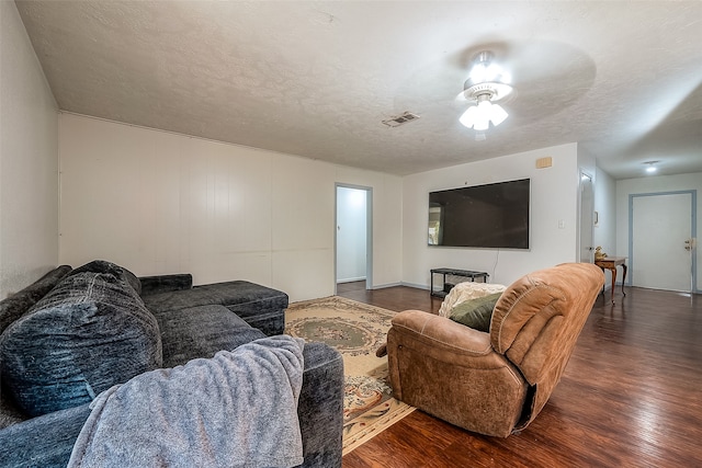 living room with dark wood-type flooring, a textured ceiling, and ceiling fan