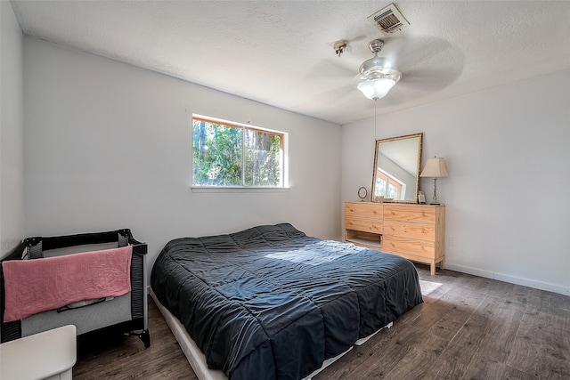 bedroom featuring ceiling fan, a textured ceiling, and dark hardwood / wood-style flooring