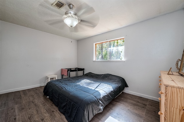 bedroom featuring dark wood-type flooring, ceiling fan, and a textured ceiling