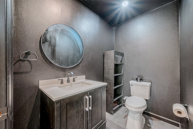 bathroom with toilet, vanity, and tile patterned flooring