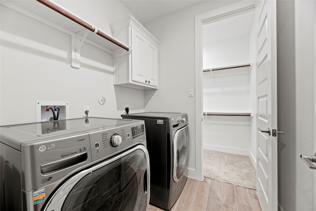 laundry area with cabinets, separate washer and dryer, and light hardwood / wood-style floors