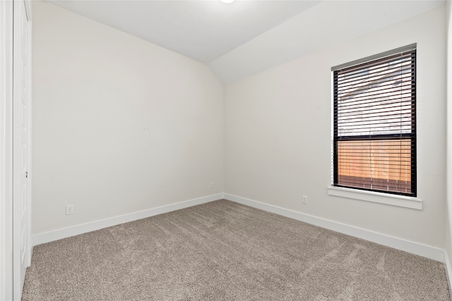 carpeted spare room featuring vaulted ceiling