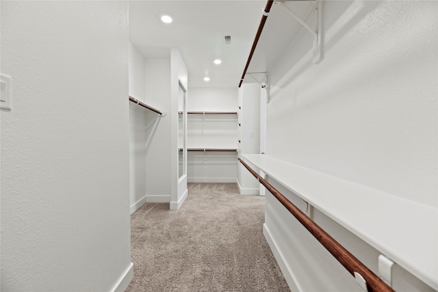 walk in closet with light carpet