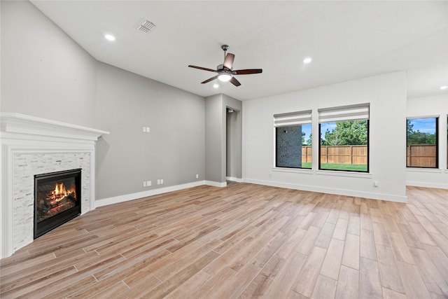 unfurnished living room with ceiling fan, light wood-type flooring, and a fireplace