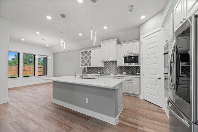 kitchen with white cabinetry, sink, a center island with sink, and light wood-type flooring