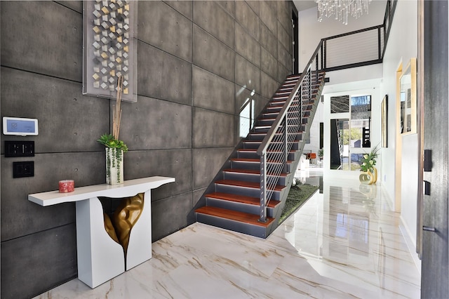 staircase with an inviting chandelier and a towering ceiling