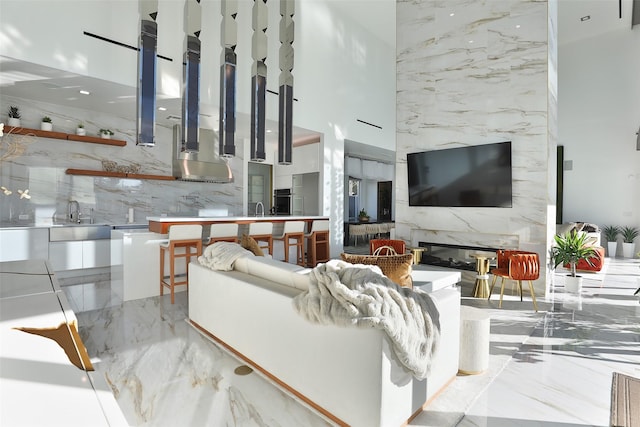 living room featuring a towering ceiling, sink, and a fireplace