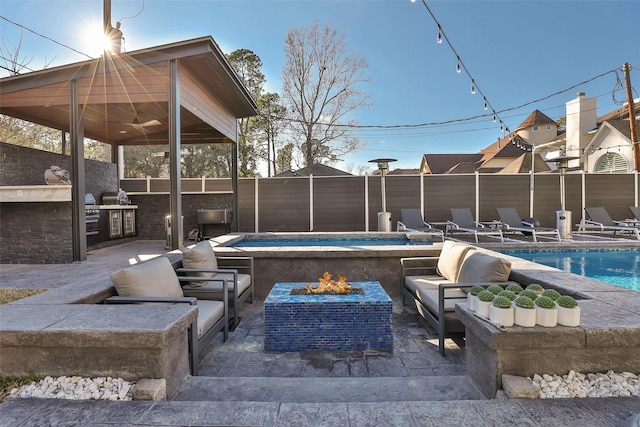 view of swimming pool with an outdoor kitchen, a hot tub, a fire pit, and a patio